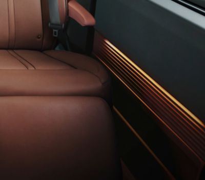 Sitz- und Seitenverkleidungsdetail im Innern eines Hyundai STARIA – beleuchtet von der Ambientebeleuchtung.