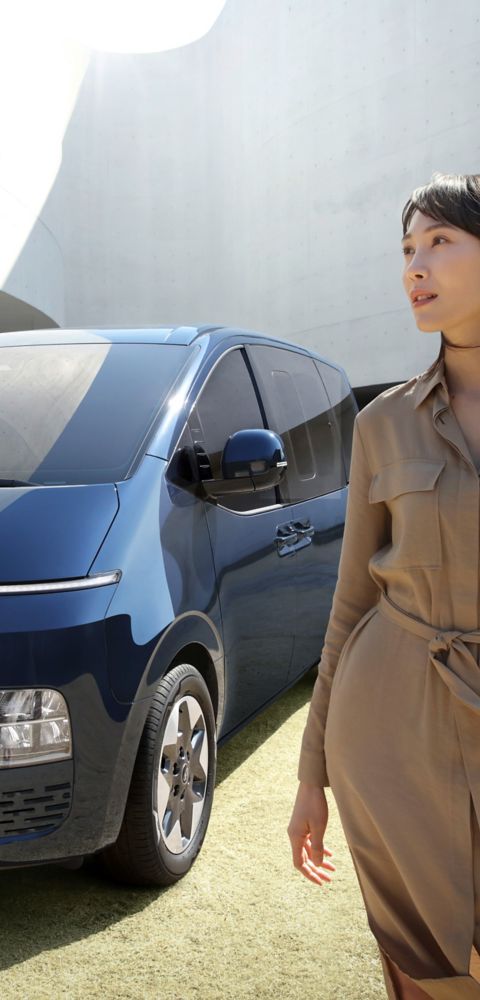Hyundai i30 seen from rear three-quarter driving on a city street in front of modern buildings.