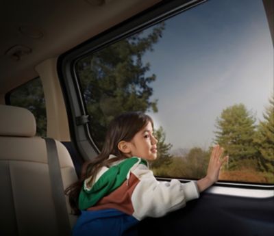 A young girl looking out the side window of the Hyundai STARIA Hybrid multi-purpose vehicle.