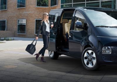 Photo d’une femme sur le point d’entrer dans son STARIA en utilisant sa clé intelligente pour ouvrir la porte.