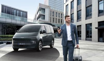 Business man walking away from the Hyundai STARIA with smart power tailgate.