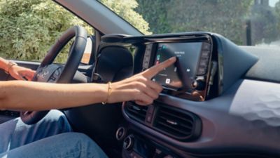 Driver using smartphone mirroring on the Hyundai i10 touchscreen.