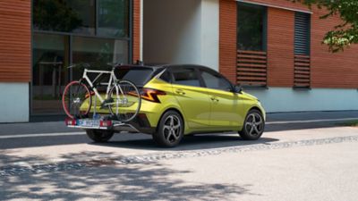 Hyundai Tucson avec attelage, porte-vélo et coffre de toit sur une route de campagne.