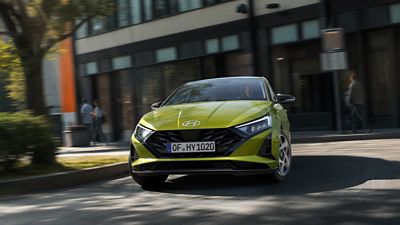 Hyundai i20 driving through a city street with buildings in the background.
