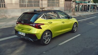 Hyundai i20 w kolorze Lucid Lime Metallic jeżdżący ulicami miasta.