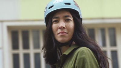 Žena s helmou na hlavě se dívá do kamery. 