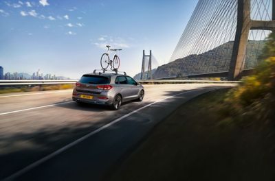 The Hyundai i30 bike carrier driving on a road towards a bridge.