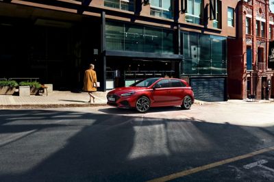 Hyundai i30 N Line stationnée dans la rue devant une façade en verre.