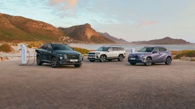 Hyundai TUCSON Plug-in, SANTA FE Plug-in und KONA Electric neben einer Ladesäule.