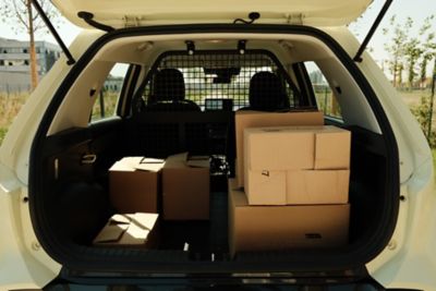 Hyundai INSTER VAN con il bagagliaio aperto, in cui si vedono delle scatole, in una strada della città.