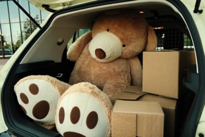 Hyundai INSTER VAN con il bagagliaio aperto, in cui si vedono delle scatole e un orso di peluche gigante, in una strada della città.