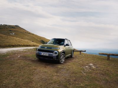 Hyundai INSTER Cross trim parked off road with hillside view.