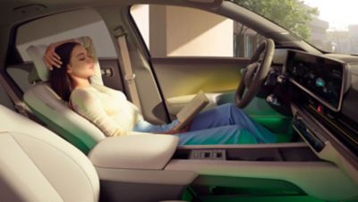 A woman leaning back in the front row relaxation seats of the Hyundai IONIQ 6 all-electric sedan.