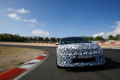The all-electric Hyundai IONIQ 5 N in camouflage at the Nürburgring racetrack shown from the front.