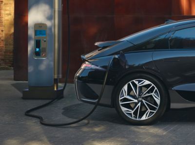 Femme courant sur un tapis roulant, avec Hyundai IONIQ en cours de recharge à l’arrière-plan.