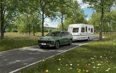 Hyundai IONIQ 9 met caravan rijdt op een weg in een natuurlijke omgeving.