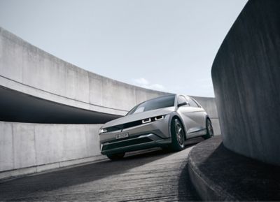Dreiviertelansicht des Hyundai IONIQ 5 in Grau, der eine kurvige Betonrampe hinunterfährt.