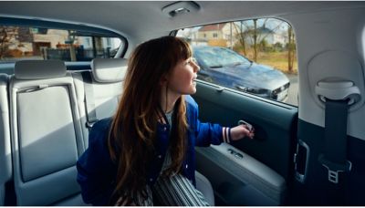 Ein Mädchen auf der Rückbank eines Hyundai IONIQ 5 blickt nach draußen und ist im Begriff, auszusteigen. 