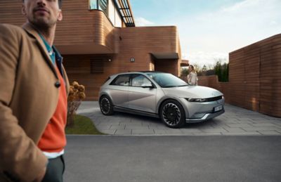 Il crossover 100% elettrico Hyundai IONIQ 5 parcheggiato nel vialetto di un moderno edificio residenziale