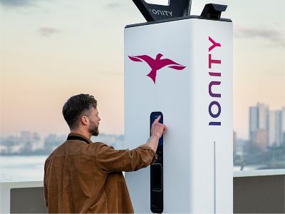 Man leaning on IONIQ 5 whilst plugged into IONITY charging station.
