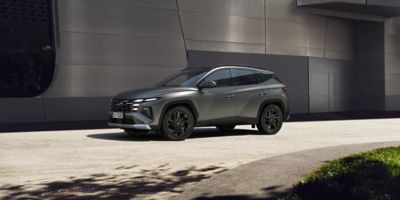 Hyundai TUCSON corre su strada davanti a un palazzo moderno