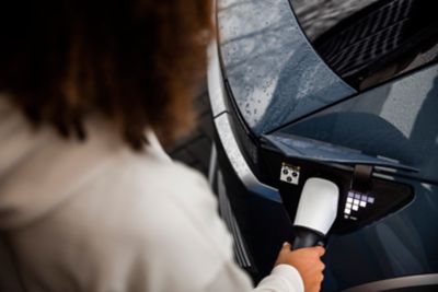 The driver of a Hyundai IONIQ 5 storing the charging cable in the front of the car.