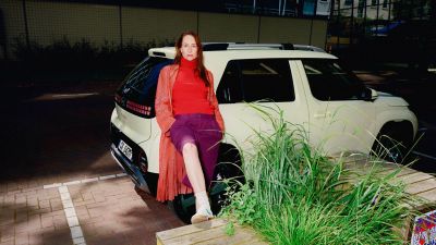 Una donna appoggiata a nuova Hyundai INSTER urban SUV elettrico