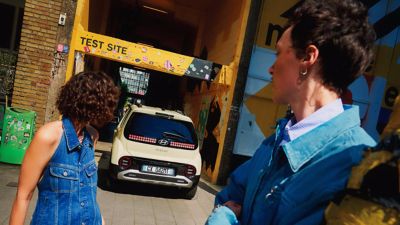 Una donna guarda il portellone posteriore di Hyundai INSTER SUV ultracompatto elettrico