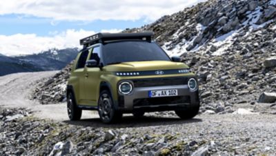 Vista frontale di Hyundai INSTER Cross mentre percorre una strada in un paesaggio roccioso