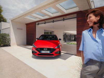 Hyundai i30 N Line di colore rosso, parcheggiata di fronte a un’abitazione