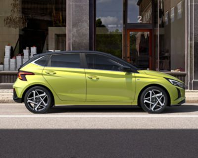 Nuova Hyundai i20 di profilo in giallo parcheggiata in un ambiente industriale