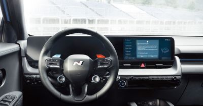 A Hyundai IONIQ 5 N high-performance EV seen from behind driving on a racetrack with trees.