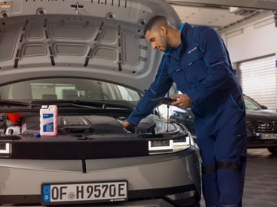 Uomo in un officina lavora sul motore di IONIQ 5 a cofano aperto