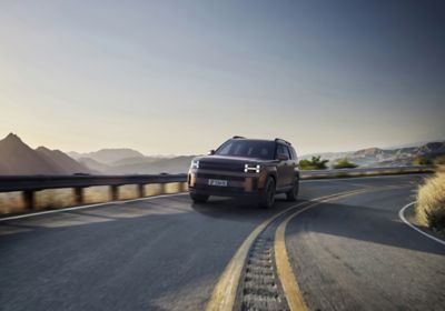 Il SUV da 5 o 7 posti Hyundai SANTA FE parcheggiata con delle montagne sullo sfondo