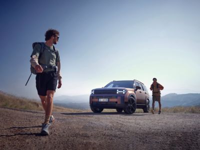 Due escursionisti che si allontanano da Hyundai Santa Fe con le montagne sullo sfondo.