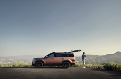 Hyundai Santa Fe parcheggiata su una prospettiva di montagna con un uomo che scatta una foto accanto al portellone posteriore.