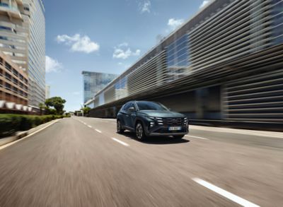 Hyundai TUCSON vista di fronte corre su strada di città in una giornata di sole