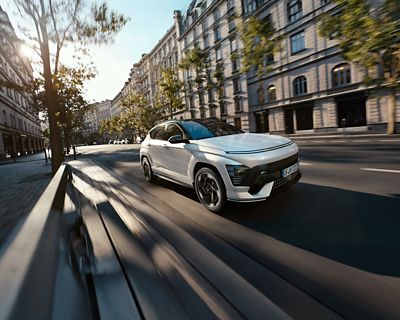 Hyundai KONA Electric roule en ville devant des bâtiments d'architecture