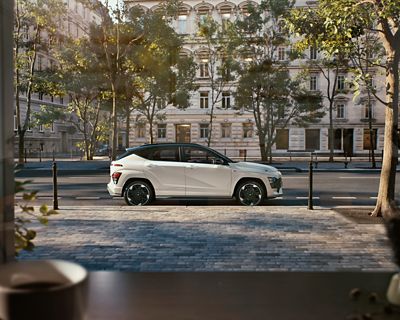 Hyundai KONA Electric N Line garé dans une rue ensoleillée devant des batiments d'architecture