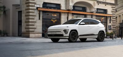 Hyundai KONA Electric Pure Edition driekwart van voren in straat met gebouw op achtergrond.