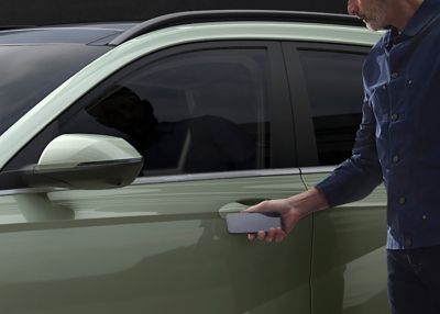 Мъж, който пробва свързаността на Hyundai KONA, като отваря вратата със своя смартфон.