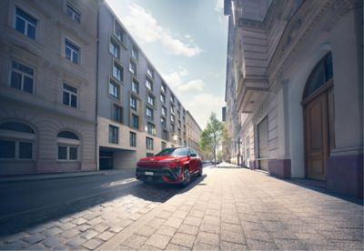 The all-new KONA N Line in red parked next to a modern building.