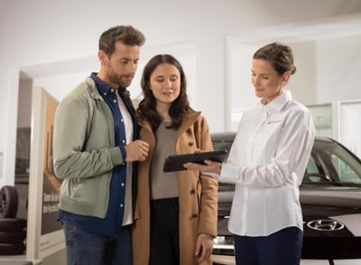 A Hyundai dealer with a tablet showing details about the Hyundai IONIQ 5 N to a couple.