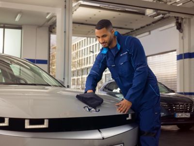 Employee cleans the engine hood of a Hyundai in the workshop.