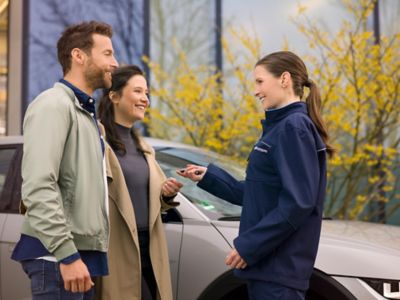 Hyundai service employee showing electric vehicle information to a customer on a tablet.