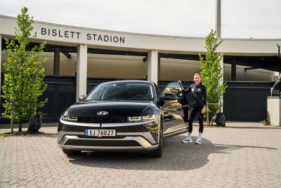 Karoline Bjerkeli Grøvdal står ved døren til IONIQ 5. Foto.