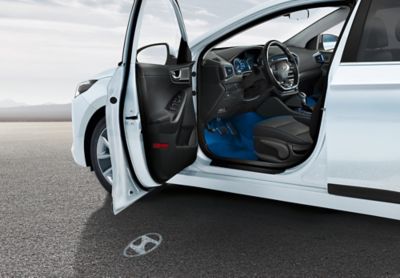 En IONIQ Electric med døren oppe og det vises innstegslys av logoen på bakken. Foto.