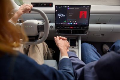 Close up of two people holding hands in front of the center touch screen of the Hyundai IONIQ 3.
