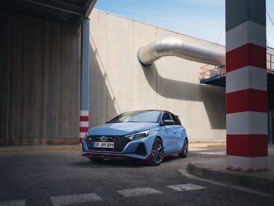 Ein Hyundai i20 N fährt an einem rot-weißen Pfeiler vorbei in eine scharfe Linkskurve.