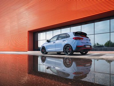 the i30 N performance hatchback from an angle, parked next to a reflective surface